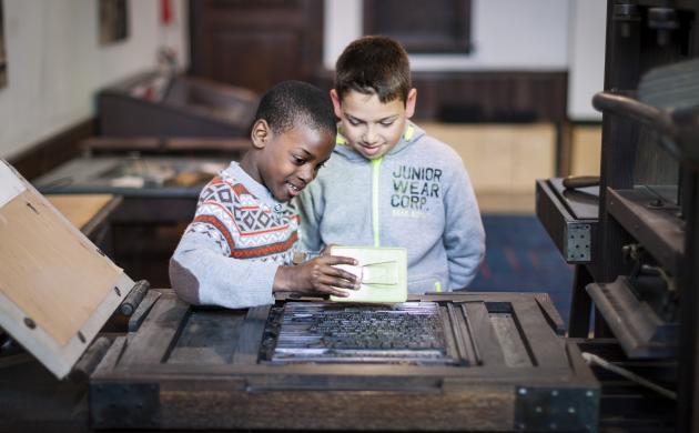 twee jongens aan de drukpers tijdens een workshop